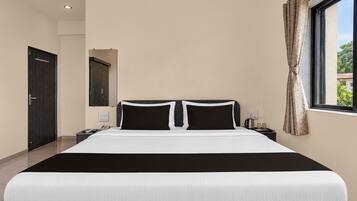 A hotel room with a large bed, a nightstand, a telephone, and a window with curtains.