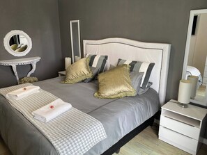 A neatly arranged bedroom with a bed, pillows, a bedside table, a mirror, and a lamp. - Stellenbosch Holiday Home (Stellenbosch)