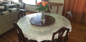 A dining table with a lace tablecloth, surrounded by wooden chairs, in a room with a sofa and a small table with a vase of flowers. - Stellenbosch Holiday Home (Stellenbosch)