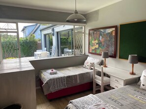 A bedroom with a bed, a desk, a chair, a window, and a painting. - Stellenbosch Holiday Home (Stellenbosch)