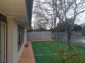 A residential property with a paved patio, a fenced yard, and a tree. - Stellenbosch Holiday Home (Stellenbosch)