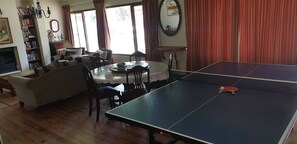 A living room with a ping pong table, a sofa, a dining table, and a bookshelf. - Stellenbosch Holiday Home (Stellenbosch)