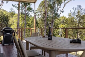 An outdoor deck with a table, chairs, a grill, and wine glasses. - Private Creek | Executive Home | Kayaks & Zipline (Sunshine Coast)