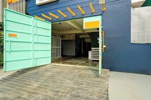 A building entrance with a green gate, a tiled floor, and a yellow ladder.