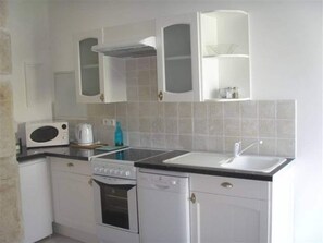 A compact kitchen with white cabinets, a microwave, a stove, a dishwasher, and a sink. - New Listing (La Cambe)