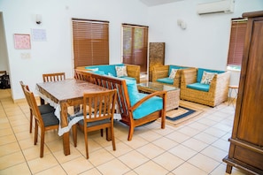 A dining area with a table and chairs, a sofa, and a decorative wall piece. - Charming 3-bedroom apartment with AC in peaceful Candolim (Arpora)
