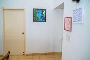 A hallway with a closed door, a framed artwork on the wall, and a tiled floor. - Charming 3-bedroom apartment with AC in peaceful Candolim (Arpora)