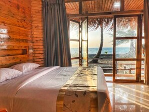 A wooden room with a bed, a view of the sea, and a thatched roof. - LuiPaz Resort Saintmartin (Saint Martin's Island)