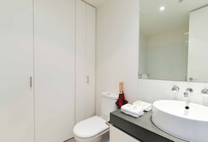 A modern bathroom with a toilet, sink, and mirror. - Spacious Seaviews (Melbourne)