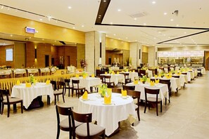 A hotel dining area with multiple round tables, each set with white tablecloths, chairs, and yellow napkins. - Kechuang Hotel (Shenzhen)
