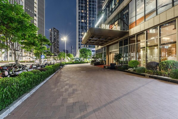 A modern building with a covered entrance, surrounded by greenery and a paved walkway. - Kechuang Hotel (Shenzhen)