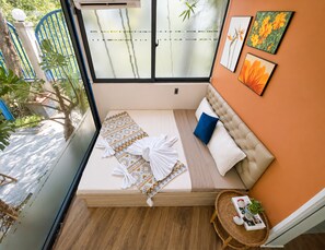 A compact bedroom with a bed, pillows, a bedside table, and a window. - The Leaf Eco Villa (Thành phố Huế)