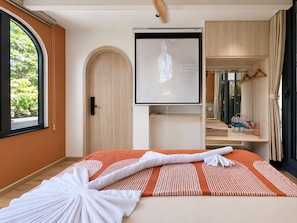 A hotel room with a bed, a television, a mirror, and a window with a view of greenery. - The Leaf Eco Villa (Thành phố Huế)