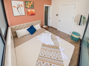 A hotel room with a bed, a bedside table, a mirror, and a door. - The Leaf Eco Villa (Thành phố Huế)