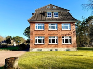 A two-story brick building with a tiled roof, multiple windows, and a well-maintained lawn. - Beach Blossom in Margarethenhof (Wyk auf Foehr)