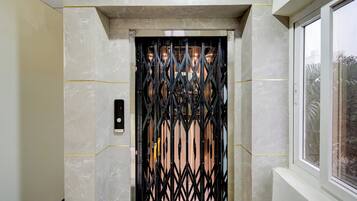 Un ascensor con una puerta metálica, un panel de control y una ventana a la derecha.