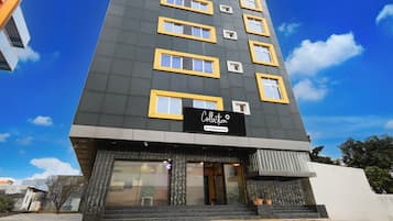 A multi-story hotel with a modern design, featuring a prominent signboard at the entrance.