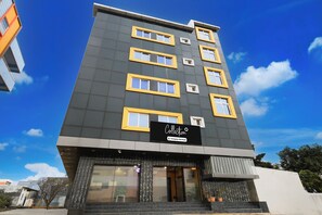 A multi-story hotel with a modern design, featuring a prominent signboard at the entrance. - Super Collection O Kollur Prime Arena (Hyderabad)