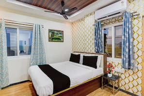 A hotel room with a bed, a nightstand, a window with curtains, an air conditioning unit, and a ceiling fan. - Super Collection O Kollur Prime Arena (Hyderabad)
