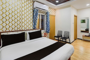 A hotel room with a bed, a window with curtains, a wall-mounted air conditioner, and a small table with a kettle. - Super Collection O Kollur Prime Arena (Hyderabad)
