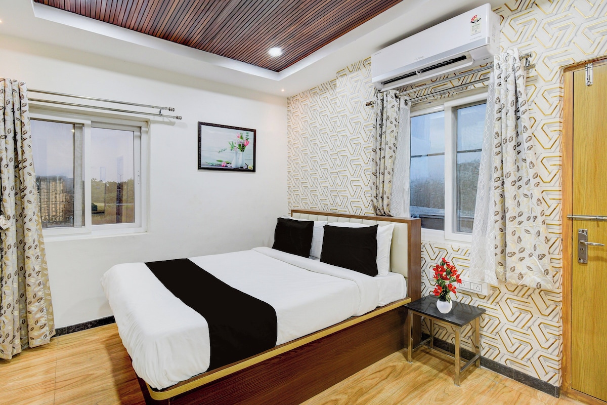 A bedroom with a bed, a nightstand, a window, and a wall-mounted air conditioner.