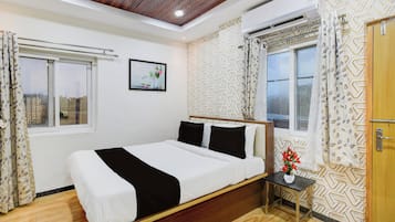 A bedroom with a bed, a nightstand, a window, and a wall-mounted air conditioner.