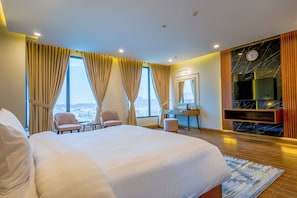 A hotel room with a large bed, two armchairs, a desk, a mirror, and a TV. - Hotel One Top City Islamabd  (Islamabad)