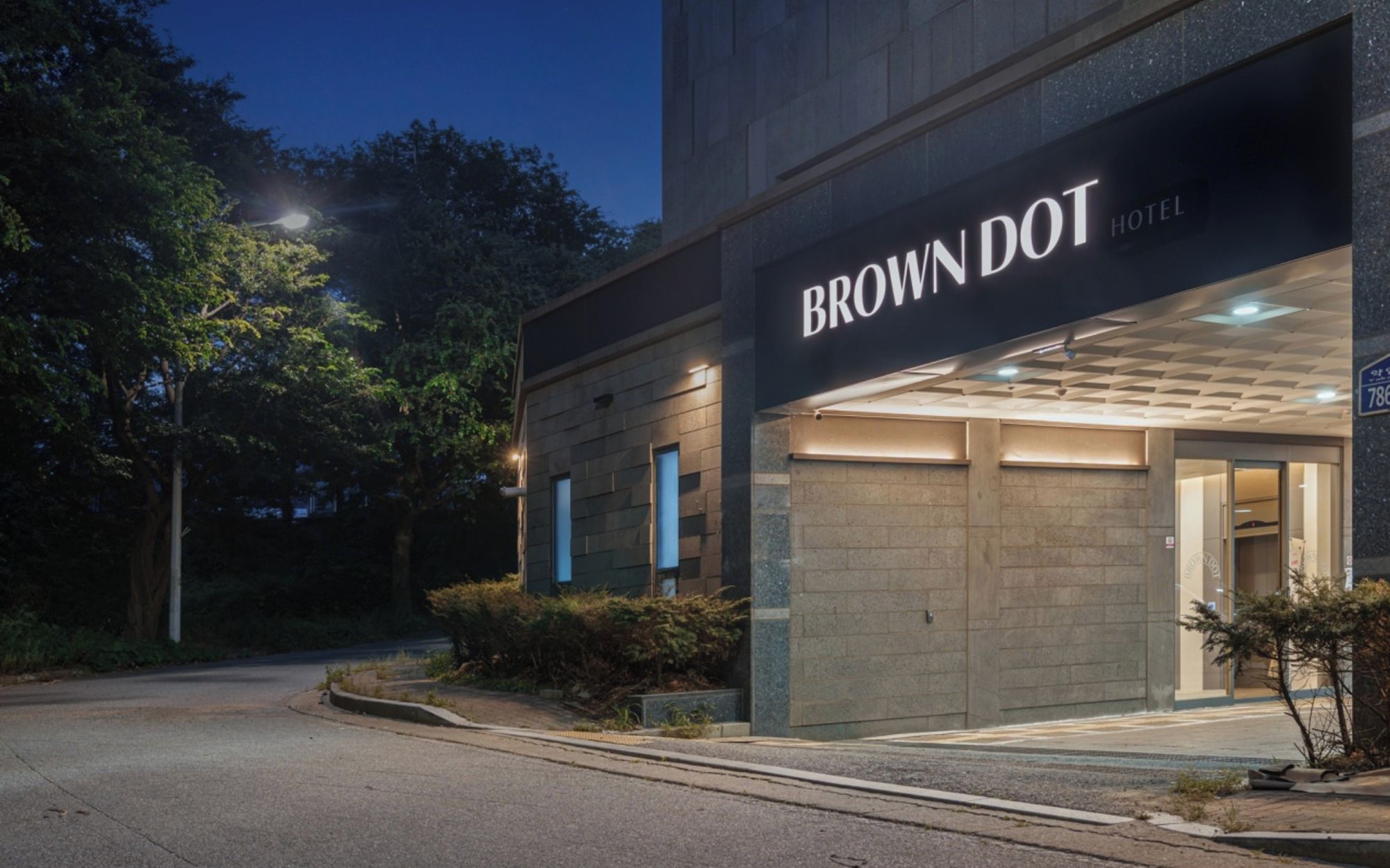 Das Brown Dot Hotel mit moderner Fassade und beleuchtetem Eingang.