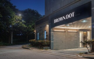El exterior del Hotel Brown Dot, con una fachada moderna y una entrada bien iluminada.