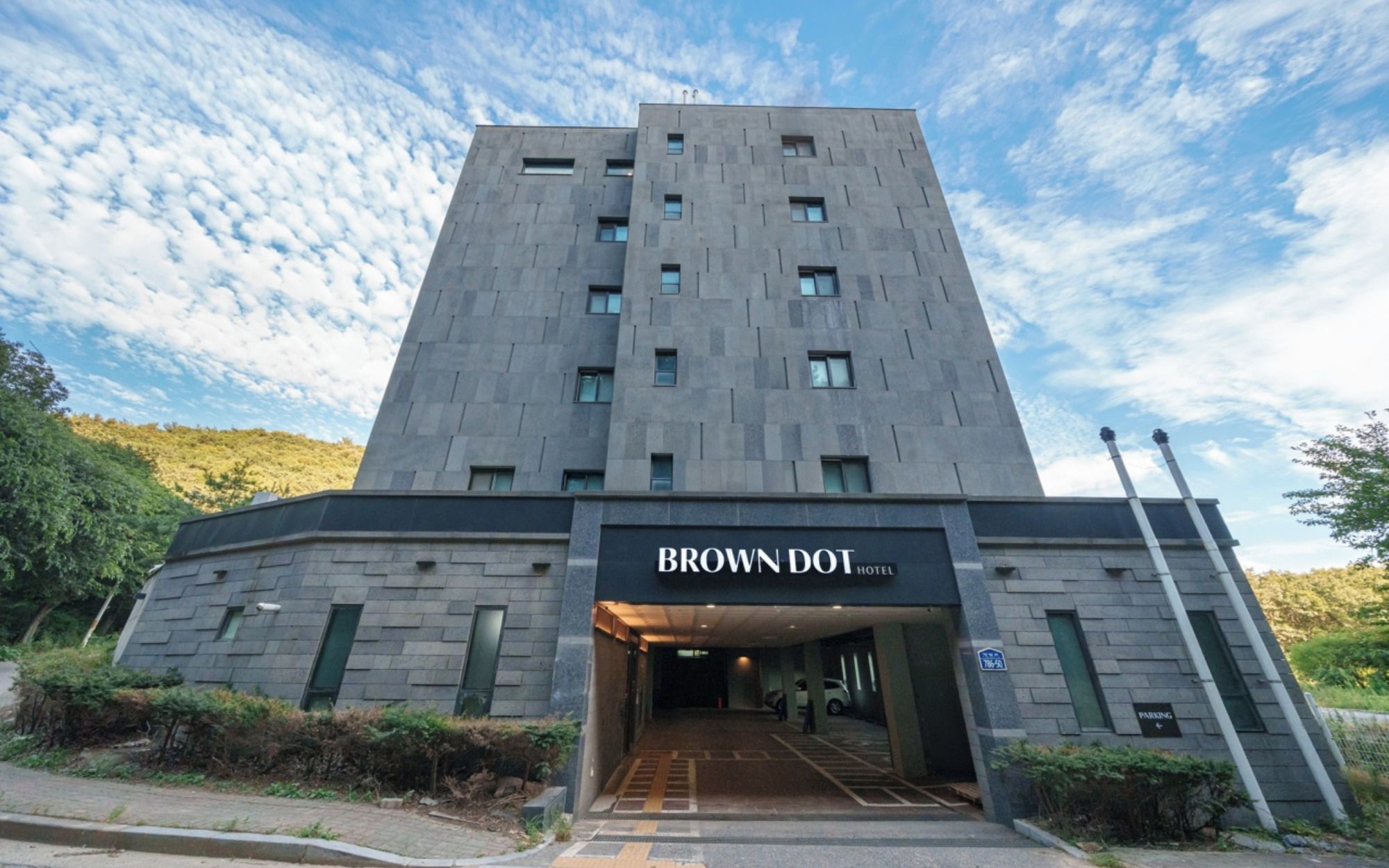 A modern hotel entrance with a sign reading 'BROWN DOT HOTEL.'