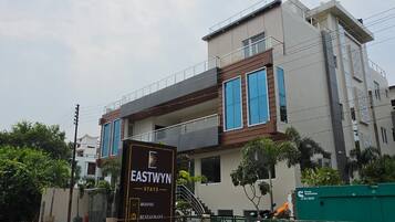 Un edificio moderno con un cartel que enumera servicios como habitaciones, un restaurante y un salón de banquetes.