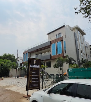 A modern building with a sign listing amenities such as rooms, a restaurant, and a banquet hall. - Eastwyn Stays (Lucknow)