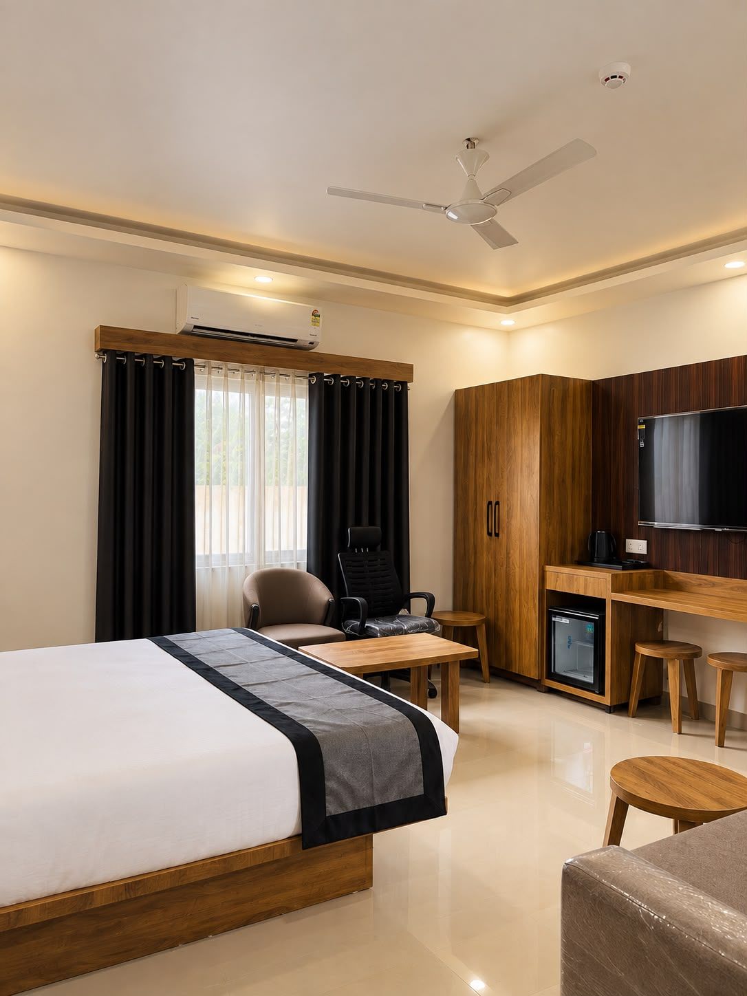 A hotel room with a bed, a desk, a chair, a television, and a minibar.
