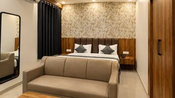 Una habitación de hotel moderna con sofá, una mesa de madera, ventilador de techo y cama con cabecera.