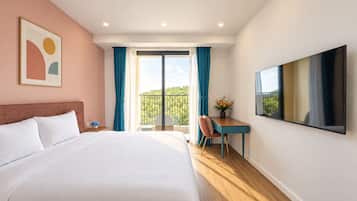Habitación de hotel con una cama grande, un escritorio, una silla, un televisor y un balcón con vistas.