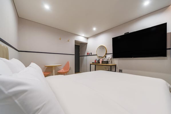A hotel room with a large bed, a desk with a mirror, a television, and a small table with chairs. - NO.25 HOTEL Namchuncheon (Chuncheon)