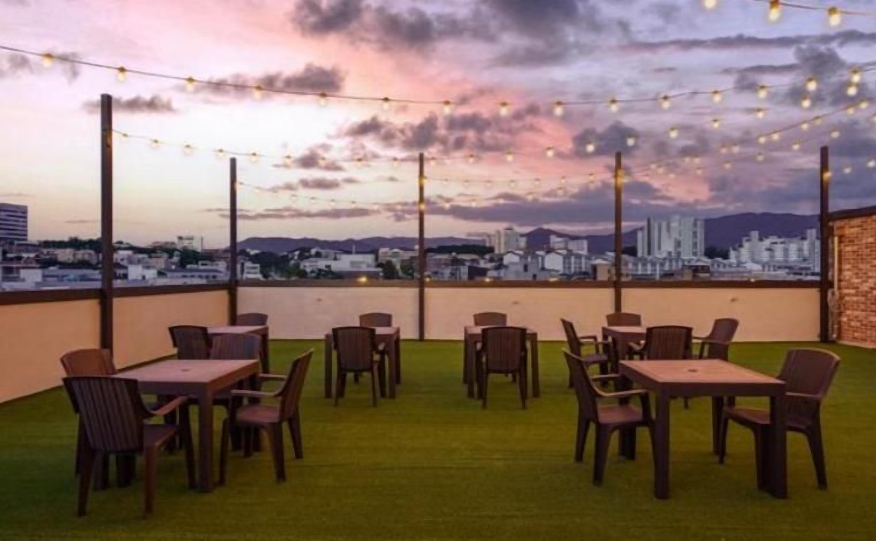An outdoor seating area with tables and chairs, overlooking a cityscape.