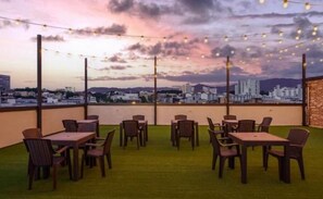 An outdoor seating area with tables and chairs, overlooking a cityscape. - NO.25 HOTEL Namchuncheon (Chuncheon)