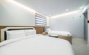 A modern hotel room with a large bed, a smaller sofa, a round table, and a window with blinds. - NO.25 HOTEL Namchuncheon (Chuncheon)
