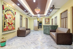 A spacious lobby with a marble floor, two sofas, a chandelier, ceiling fans, and a large religious painting. - Super Hotel O Seven Road Junction (Srikakulam)