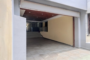 A hallway with a patterned floor, a staircase leading to an upper level, and a door with a wooden frame.