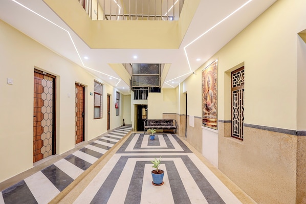A hotel corridor with a central staircase, a sofa, and a potted plant.