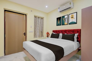 A hotel room with a bed, a door, an air conditioning unit, and two framed artworks on the wall. - Super Hotel O Seven Road Junction (Srikakulam)