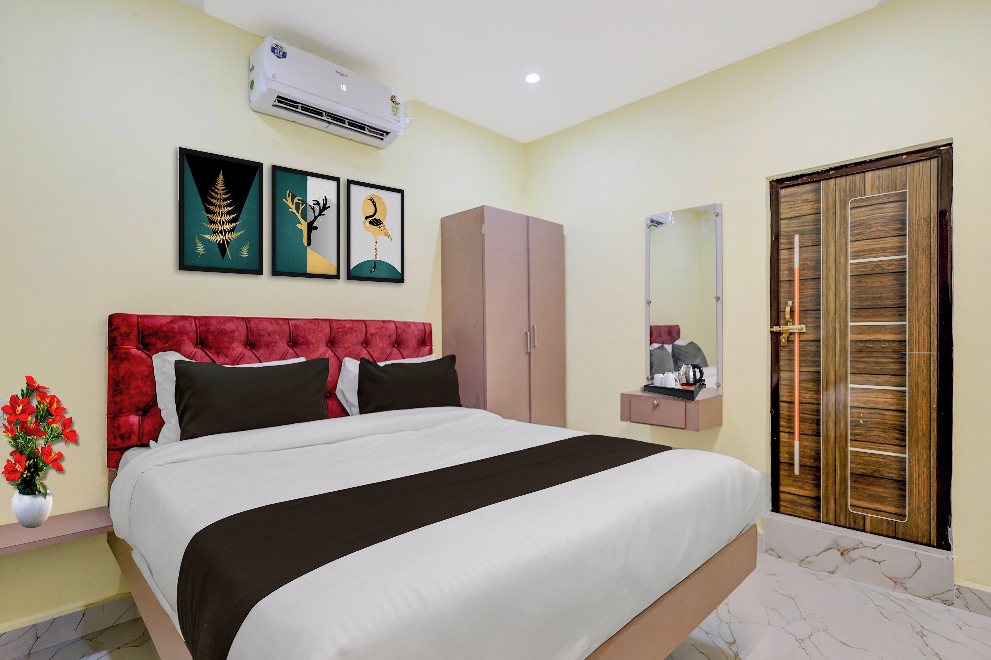 A hotel room with a bed, a wardrobe, a mirror, and a wall-mounted air conditioner.