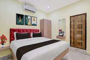A hotel room with a bed, a wardrobe, a mirror, and a wall-mounted air conditioner. - Super Hotel O Seven Road Junction (Srikakulam)