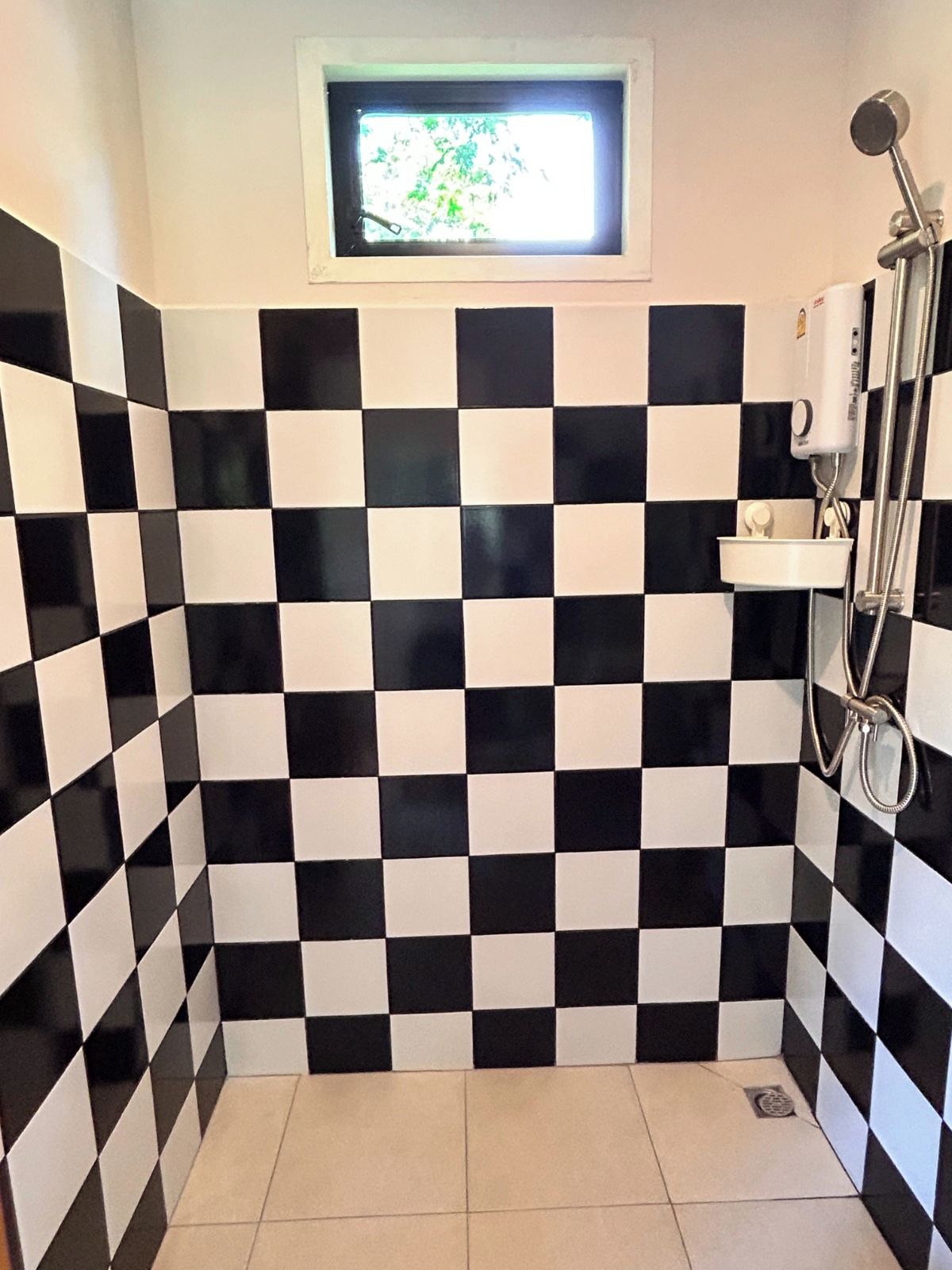 Ein Badezimmer mit schwarz-weiß karierten Fliesen, einem Fenster und einer Dusche.