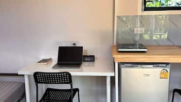 A compact kitchenette with a refrigerator, a small sink, and a window with a view of greenery.