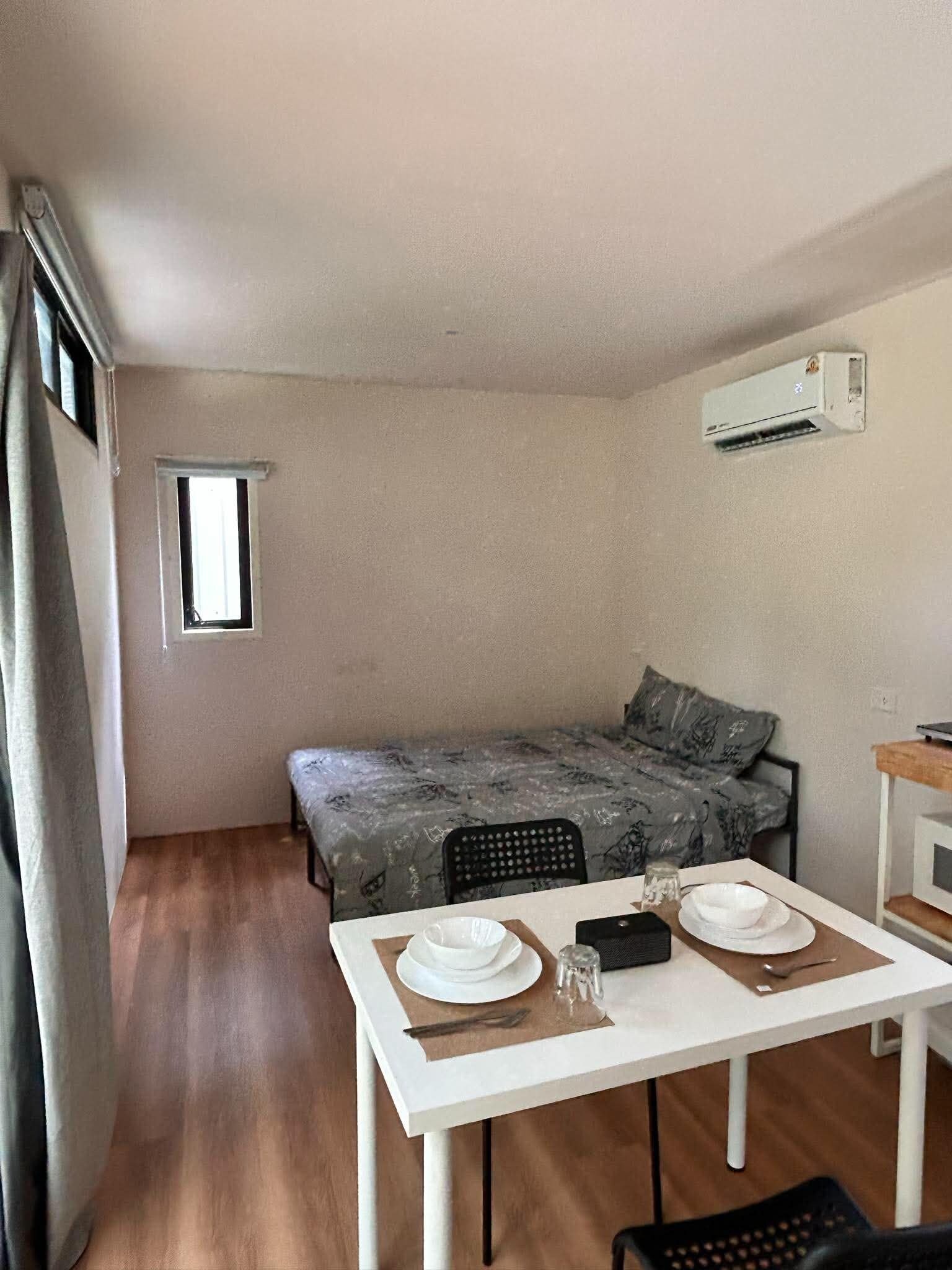 A compact room with a bed, a small table set for two, and a window.
