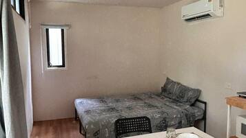 A compact room with a bed, a small table set for two, and a window.