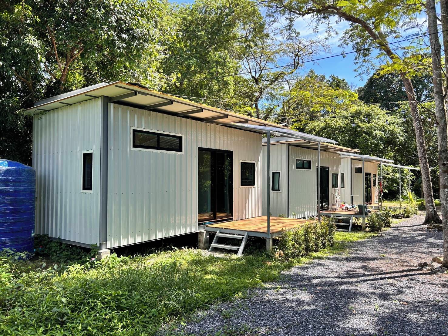 Een rij vakantiehuisjes met houten terrassen, omgeven door groen en bomen.